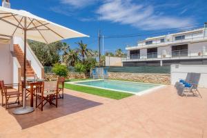 a patio with an umbrella and a swimming pool at Villa Payu in Ciutadella