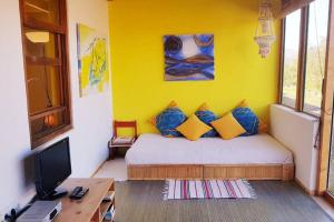 een slaapkamer met een bed met een gele muur bij Alegría Aire - Eco Retreat Finca Artis Tirma in Tarajalejo