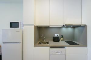 een keuken met witte kasten, een wastafel en een koelkast bij Apartamentos enfrente del Museo Dalí in Figueres