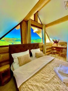Casa Crăciun في Valea Nandrului: غرفة نوم بسرير كبير مع نافذة كبيرة