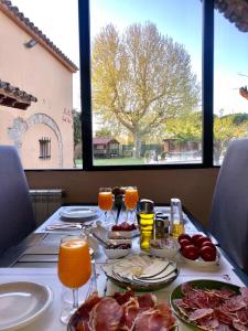 una mesa con platos de comida y bebida y una ventana en Masia Ca La Caputxeta & Golf, en Castelló d'Empúries