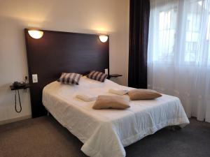 a bedroom with a large bed with two pillows on it at La Croix Blanche in Beaurepaire-en-Bresse