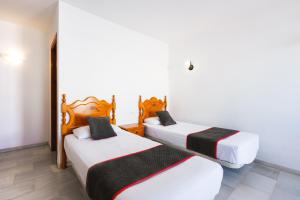 two beds in a room with white walls at Apartamentos Pepe Mesa in Nerja