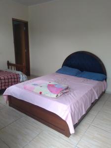 uma cama com um cobertor rosa e almofadas azuis em Pousada Santa Felicidade com garagem J em Curitiba
