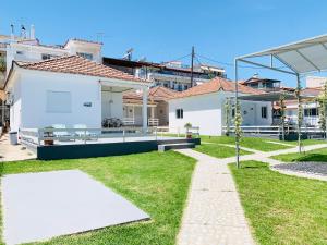 a backyard with a white house and grass at Seaside Bungalows Petalidi in Petalidi