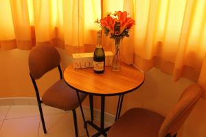 una mesa con una botella de vino y flores. en Hotel y Restaurante Roma, en Ica