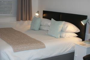 オールドバラにあるTirah Guest Houseのベッド(白い枕、黒いヘッドボード付)