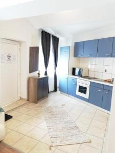 a kitchen with blue cabinets and a tile floor at Apartmenthaus beim LKH Graz in Graz