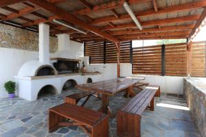 un patio con mesas de madera y un horno de pizza en Gorgeous Eco Friendly Seaside Villa Nefeli, en Schinias