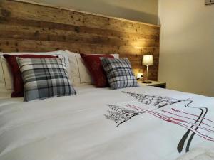 a white bed with red pillows and a wooden headboard at Le Bifore in valle in Predazzo