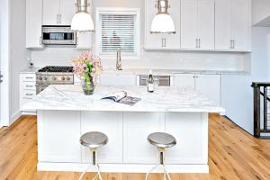 a white kitchen with a large island with two stools at Boulders Way - 15 in Telluride