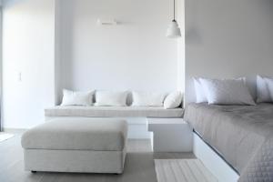 a white room with two beds and a chair at The Hidden Gem in Skiathos Town