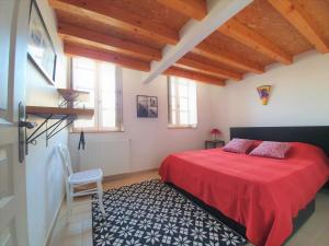 ein Schlafzimmer mit einem roten Bett und einem Stuhl in der Unterkunft Maison de village façon Loft, avec cour et airco, dans le centre historique in LʼIsle-sur-la-Sorgue
