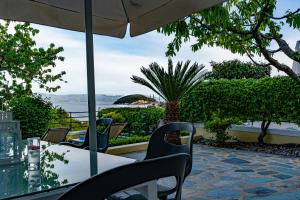 a table with chairs and an umbrella on a patio at Sea Path Apartment in Paleo Tsifliki