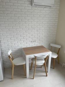 una mesa de madera, 2 sillas y una pared blanca en Лучшие апартаменты для размещения с детьми возле Днепра, центр в пешей доступности en Cherkasy