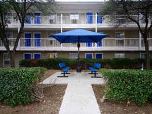 una sombrilla azul y sillas frente a un edificio en InTown Suites Extended Stay Carrollton TX - Westgrove Drive, en Carrollton