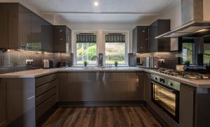 a kitchen with dark brown cabinets and a sink at Modern 2 Bedroom House in Portree
