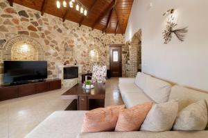 a living room with a couch and a tv at Villa La Isla with Private Pool in Mouzákion