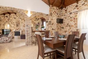a dining room with a table and a stone wall at Villa La Isla with Private Pool in Mouzákion