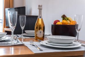 a table with a bottle of wine and a bowl of fruit at The Old Library - Modern apartment with rooftop terrace near the train station in Newbury