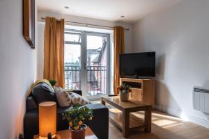 a living room with a couch and a tv and a window at The Old Library - Newbury Town Centre - Within easy reach of Train Station and Racecourse - Excellent road links via the A34 and M4 in Newbury