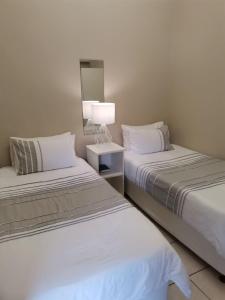 a bedroom with two beds and a lamp in it at Muir Holiday Apartments in Stilbaai