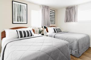 InTown Suites Extended Stay Raleigh Garner NC في جارنر: سريرين في غرفة نوم بجدران بيضاء