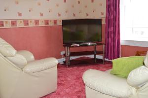 a living room with two chairs and a flat screen tv at Kirk View holiday apartment in Kirkcaldy