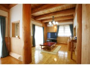 ein Wohnzimmer mit einem Tisch und einem TV in der Unterkunft Log house for 12 people - Vacation STAY 33957v in Minamioguni