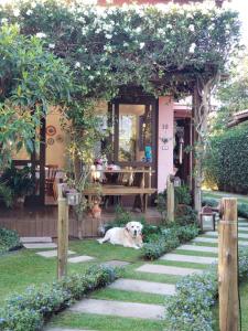 a dog laying on the grass in front of a house at Pousada Vila Rosada in Florianópolis