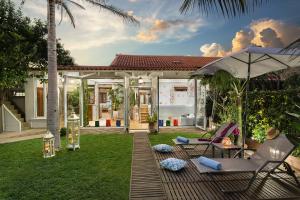 un patio trasero con sillas, una sombrilla y una casa en Villa Splantzia - Heated pool - Garden, en La Canea