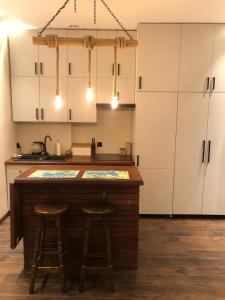 una cocina con armarios blancos y 2 taburetes en un mostrador en Friends Apartment en Słupsk