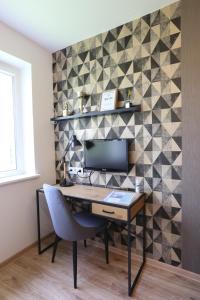 a desk with a chair and a monitor on a wall at Modern 2 Rooms Apartment in Kaunas