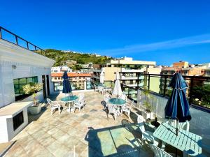 a patio with tables and chairs and umbrellas on a balcony at LOFT LUXO VISTA MAR PRAINHA até 5 PESSOAS in Arraial do Cabo