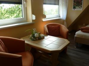 Zimmer mit 2 Stühlen, einem Tisch und 2 Fenstern in der Unterkunft Kleines Ferienhäuschen in Kritzmow
