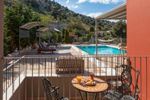 a balcony with a table and chairs next to a pool at Dalasvillas SkalaAcqua in Skala Kefalonias