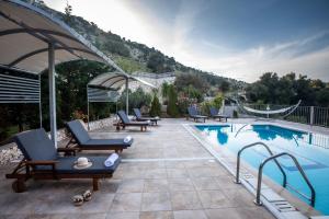 a swimming pool with lounge chairs next to a mountain at Dalasvillas SkalaAcqua in Skala