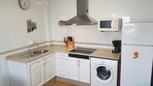 a white kitchen with a sink and a refrigerator at El Desván Escondido in Conil de la Frontera