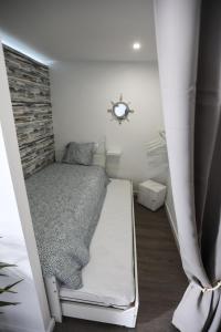 Dormitorio pequeño con cama y pared de ladrillo en Vina's Beach House - 2 minute walk to the beach, en Costa da Caparica