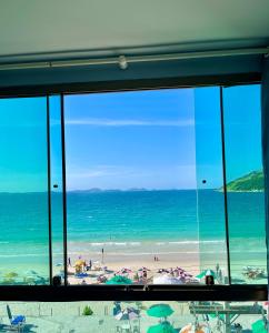 uma vista para a praia a partir de uma janela em LOFT LUXO VISTA MAR PRAINHA até 5 PESSOAS em Arraial do Cabo