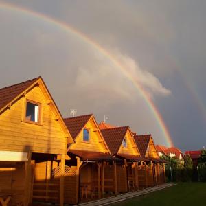 a rainbow over a row of wooden cabins at DorJan - Domki Letniskowe in Dziwnówek