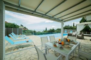 a patio with a table and chairs and a pool at Villa Hera-The infinity blue in Nisakion