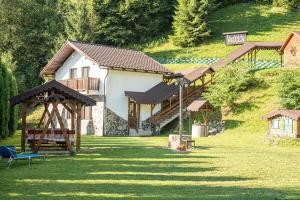 a house on a hill with a bench in the grass at Casa Bella in Vadu Moţilor