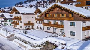 une maison dans la neige avec des toits recouverts de neige dans l'établissement Hotel Vernel, à Santa Cristina Valgardena