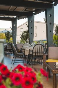 un patio con mesas, sillas y flores rojas en Hotel Keto en Podgorica