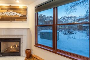 a room with a fireplace and a view of snow covered mountains at Ballard South in Telluride