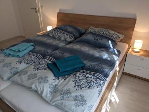 Bett mit schwarzer und weißer Bettwäsche und blauen Kissen in der Unterkunft Ferienwohnung MonSevi in Wackersberg