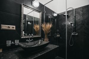 La salle de bains noire est pourvue d'un lavabo et d'un miroir. dans l'établissement Room42 - Suites & Apartments, à Esztergom