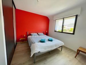 ein Schlafzimmer mit einer roten Wand und einem Bett in der Unterkunft maison moderne à guidel plage in Guidel