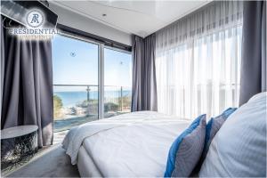 ヤロスワビエツにあるPrezydencki Apartamentyのベッドルーム1室(ベッド1台付)、海を望む大きな窓が備わります。
